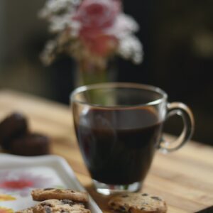 black liquid in clear glass mug beside brown bread on brown wooden table